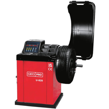 A red and black professional automotive wheel balancer, model U-820 by GEO, with a tyre mounted on the spindles and a black protective cover open behind it, shown against a plain white background.