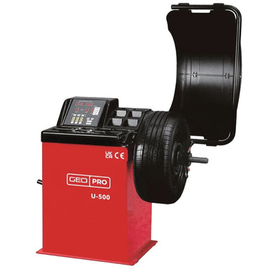 A red and black professional automotive wheel balancer, model U-500 by GEO, with a tyre mounted on the spindles and a black protective cover open behind it, shown against a plain white background.